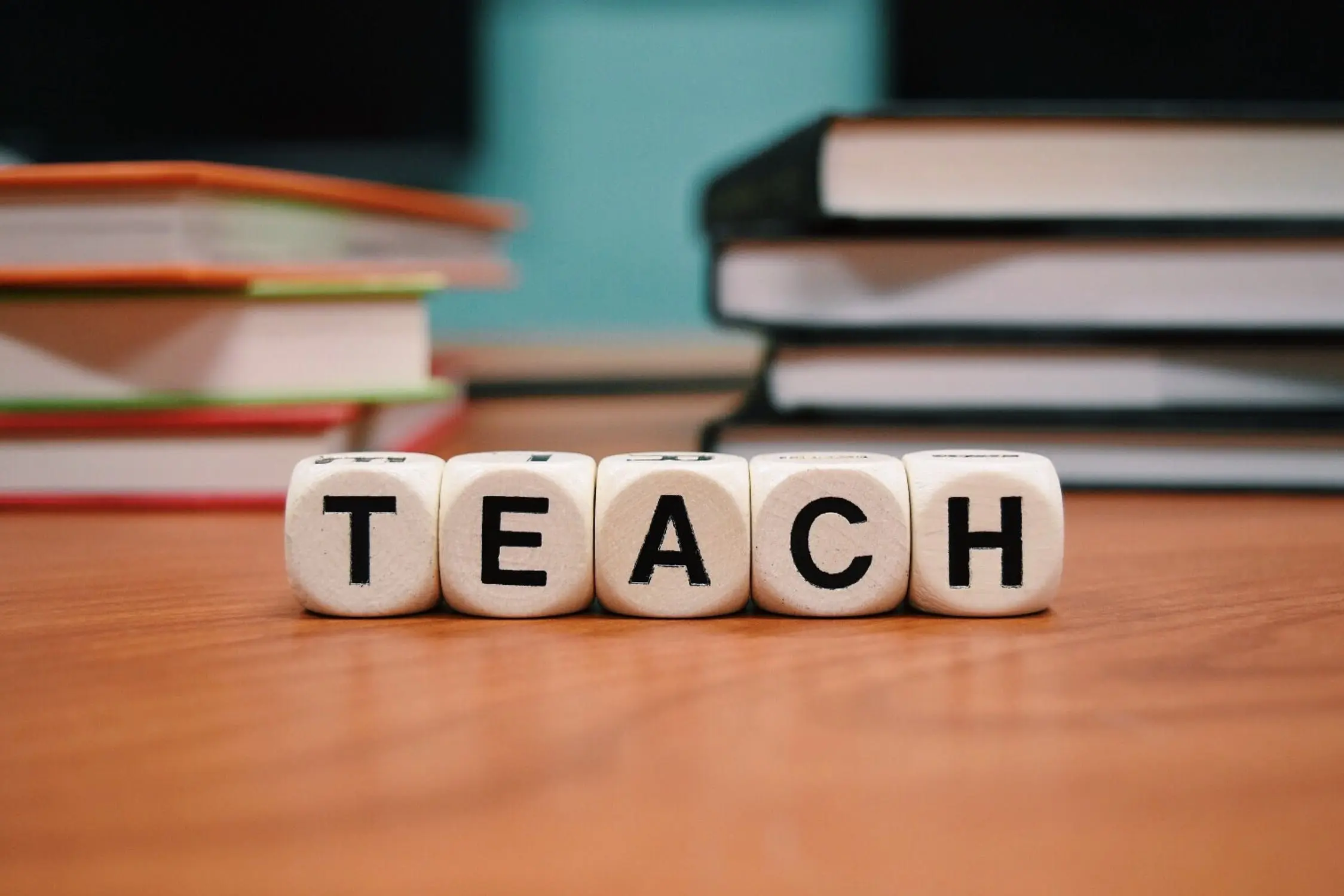 "Teach" spelled out with wooden letter blocks