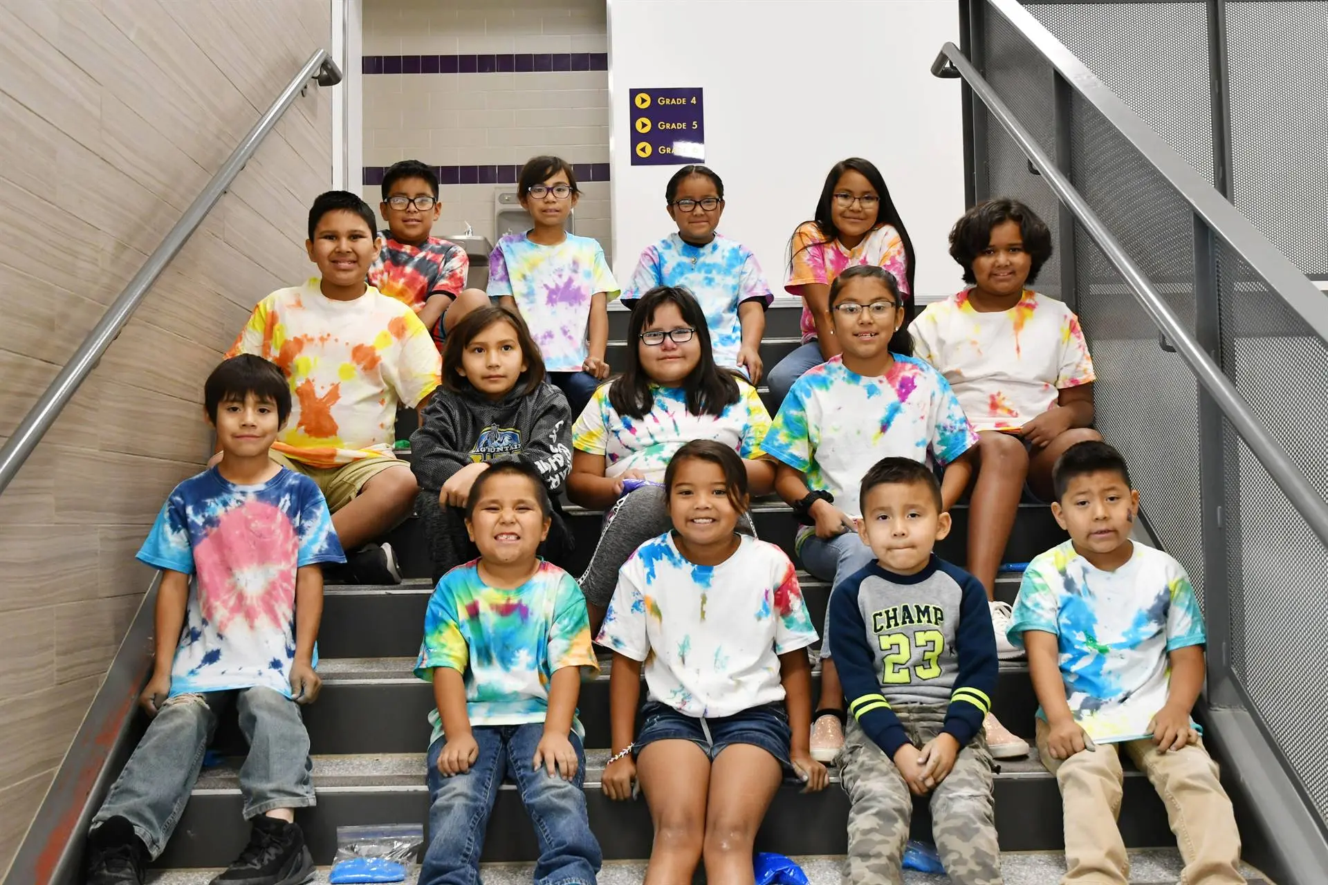 Students on a set of stairs showing off the tie-dyed shirts they made