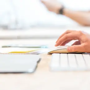 Hand using a wireless keyboard and mouse with a laptop