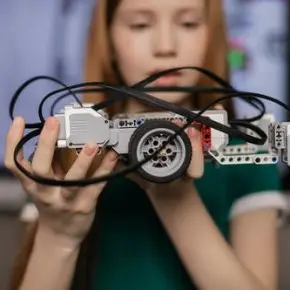 Student holding up a small wheeled robot she built