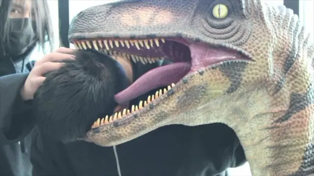 Student putting his head in the mouth of a dinosaur sculpture, as captured by the photography club