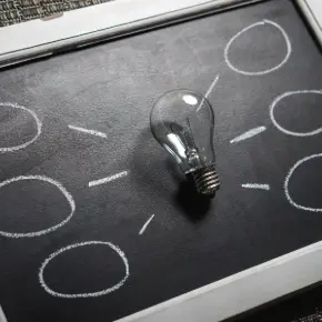 Lightbulb on a mini blackboard with clack lines and bubbles (indicating thoughts)