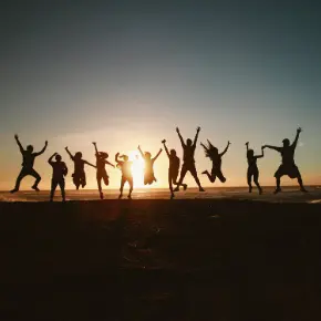 People in silhouette against the sunset jumping in the air