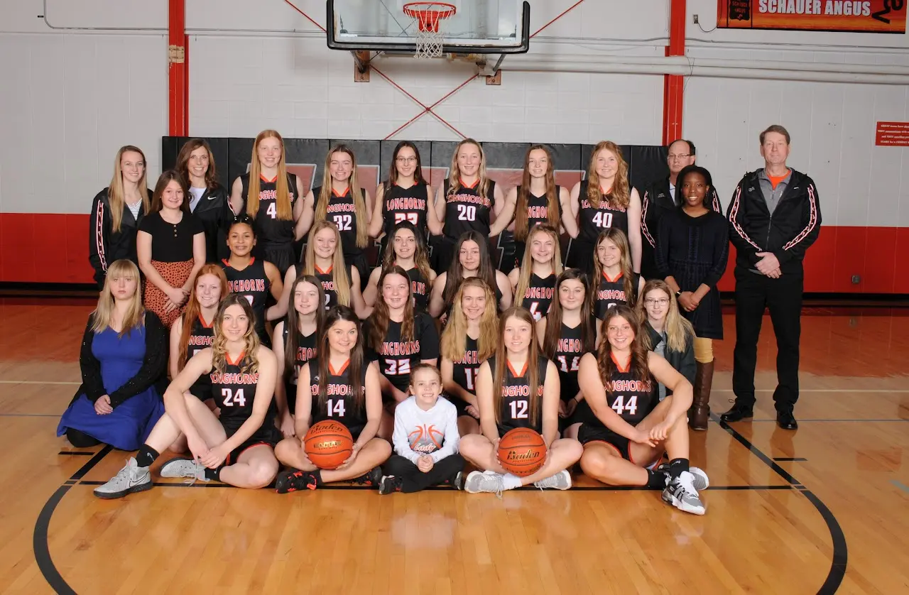 Group team photo in gym in front of basketball hoop