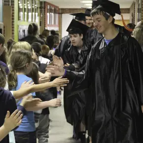 young and old students high fiving while passing in the hallway